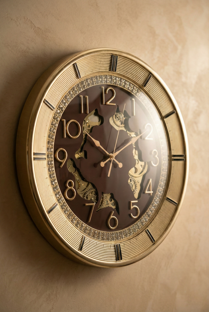 16-inch luxury designer wall clock with a gold metallic frame, brown dial, crystal-studded inner ring, raised gold numerals and exposed decorative gears mounted on a textured beige wall.