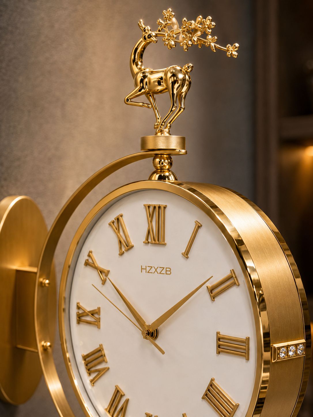 A close-up of a gold-toned wall clock with a white dial, Roman numerals, decorative hands, and a deer figurine on top. The brand name HZXB is visible on the clock face.