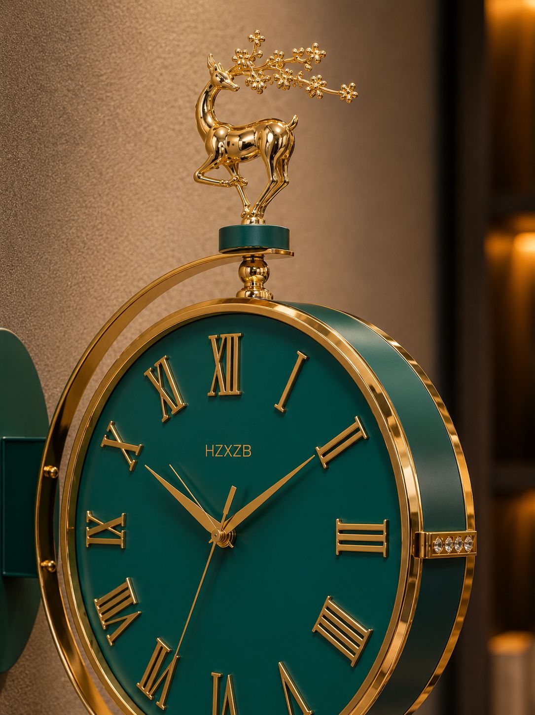 A close-up of an ornate wall clock with a dark teal-green face and gold-tone Roman numerals, surrounded by a gold-tone frame. The top is decorated with a gold deer figurine holding a flowering branch.