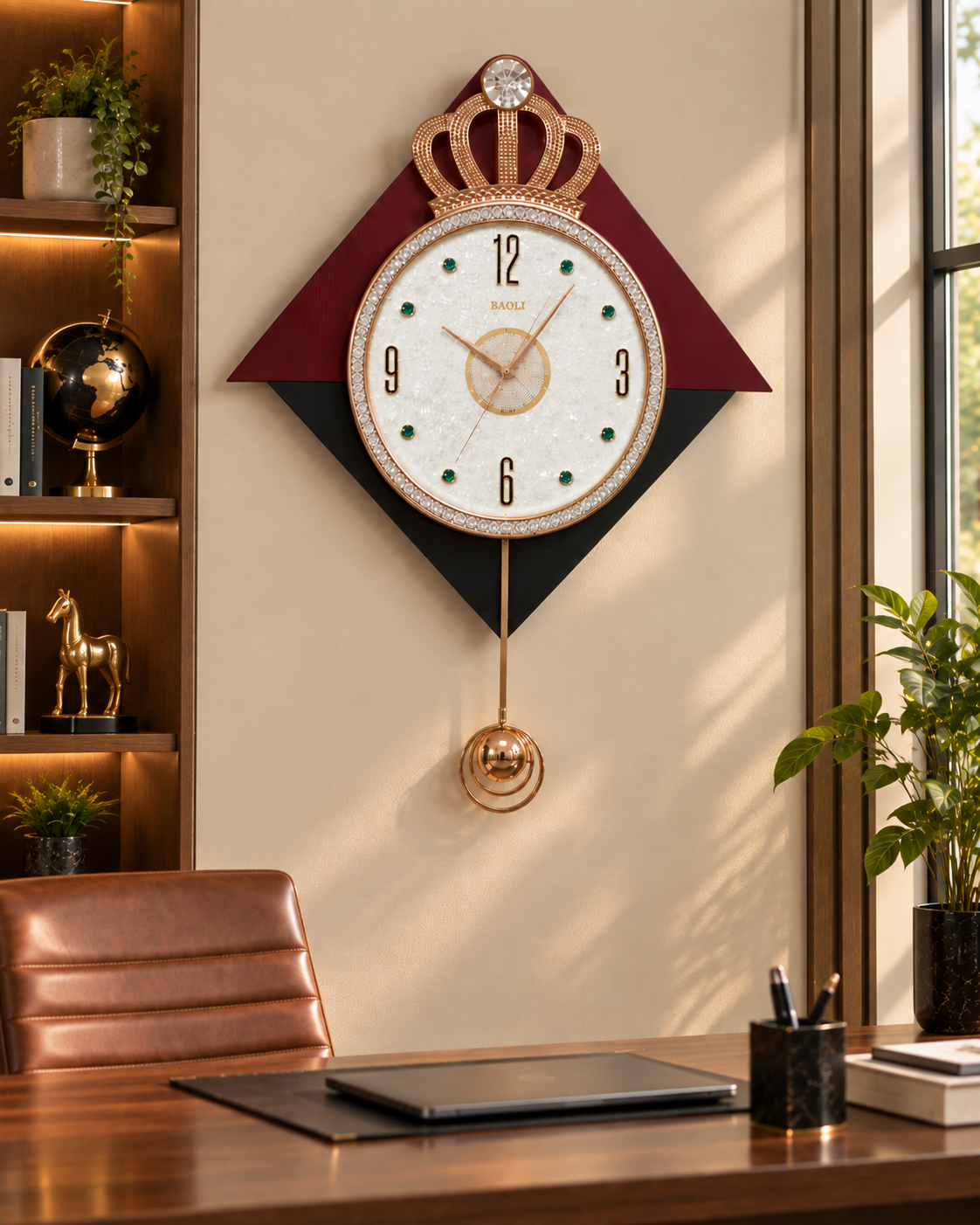 A decorative wall clock mounted above a wooden desk in a styled home office. The clock features a crown motif at the top, a white dial with black Arabic numerals, and a geometric frame in deep red and black.