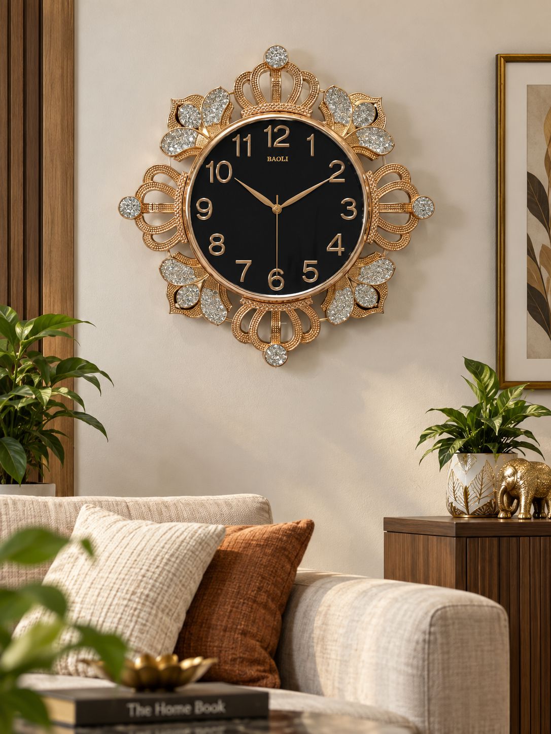 A decorative wall clock with a black face and ornate gold-tone frame, mounted on a beige wall above a sofa in a styled living room.