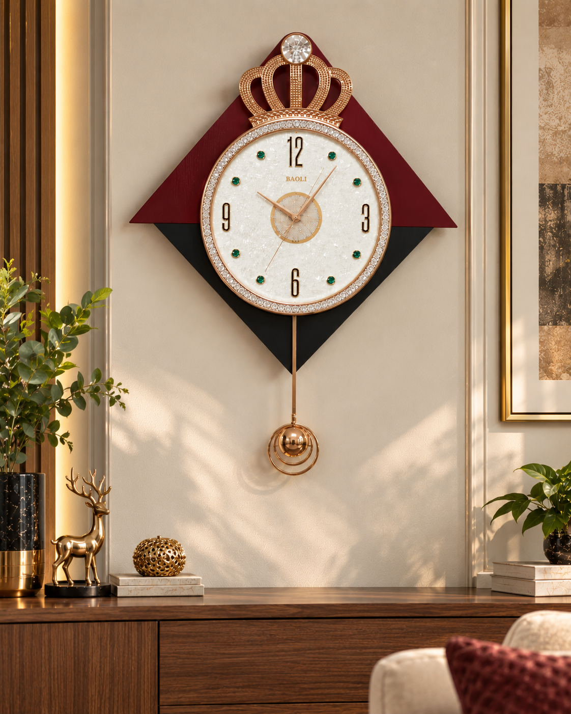 A decorative wall clock with a crown motif and a round white face, mounted on a beige wall above a wooden console table. The clock features a gold-tone crown and pendulum, a black and burgundy geometric background, and green dot hour markers.