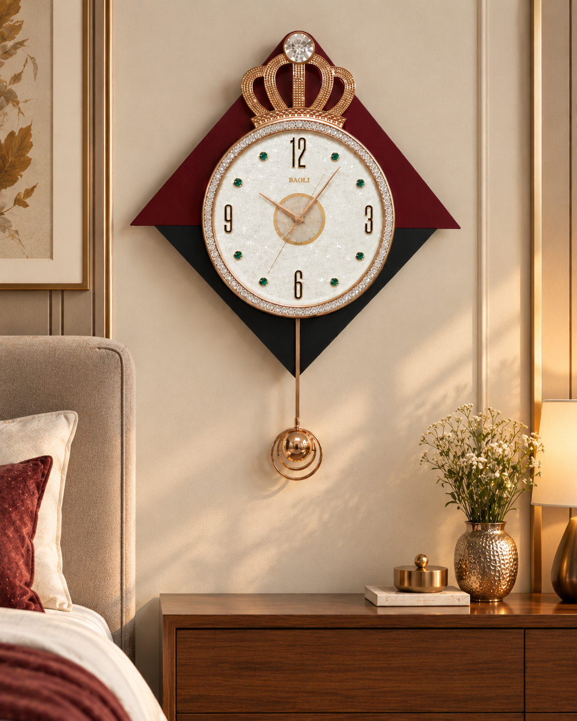 A decorative wall clock with a crown motif and a white face, mounted above a wooden bedside table in a styled bedroom. The clock features a white face with gold hands, black numerals, green dot hour markers, and a maroon and black diamond-shaped frame.