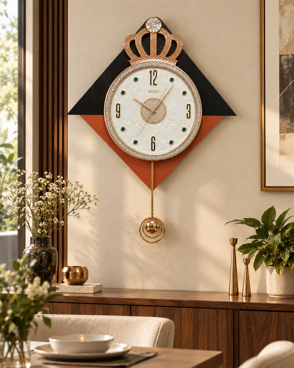 A decorative wall clock with a crown motif and gold-tone pendulum, mounted on a beige wall above a wooden console table in a styled interior setting.