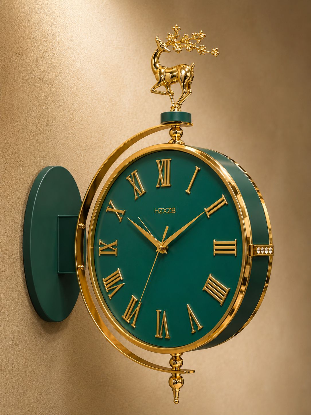 A decorative wall clock with a dark teal-green face and frame, gold Roman numerals, gold hands, and a gold deer figurine on top, mounted on a beige wall.