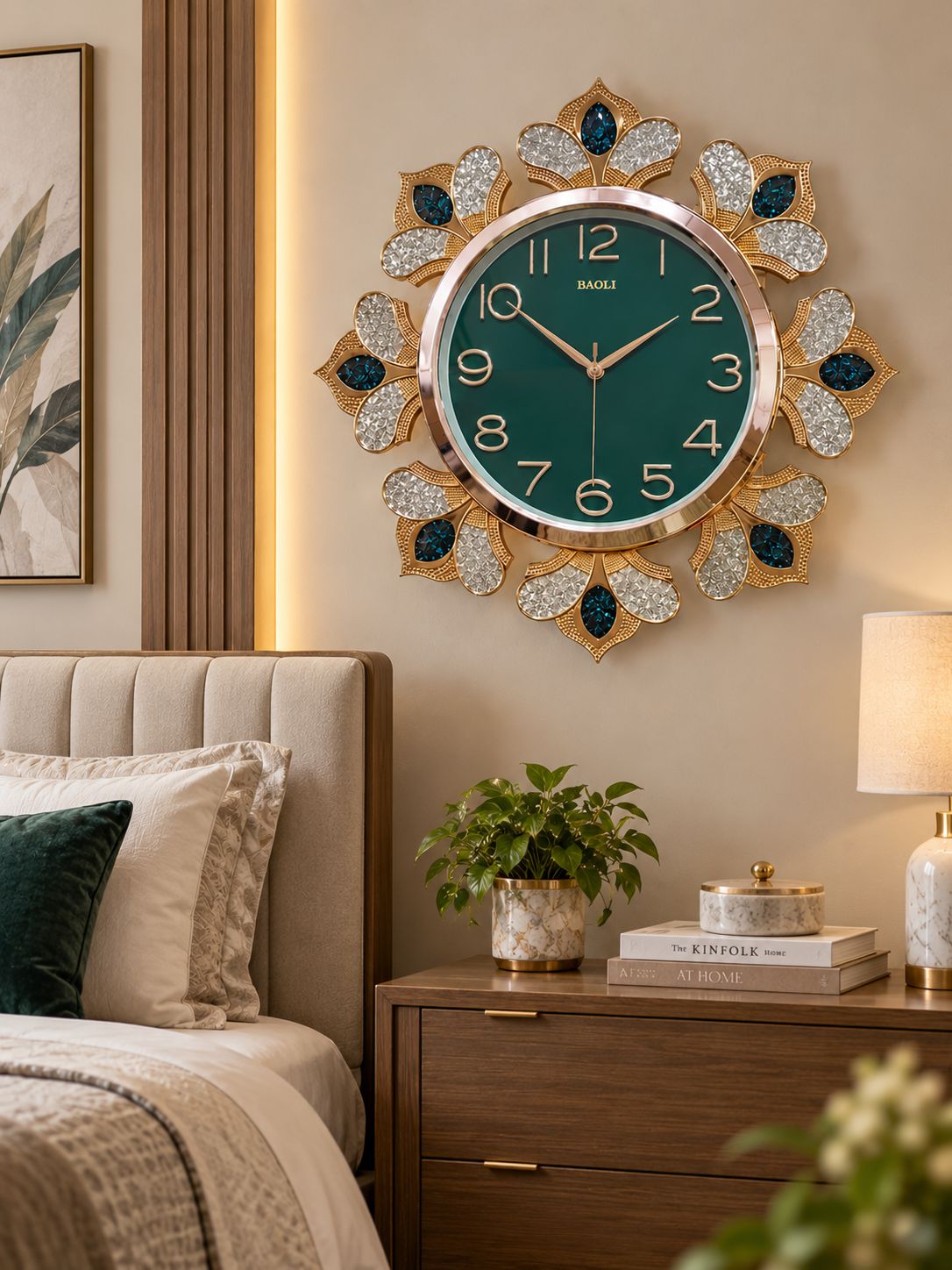 A decorative wall clock with a round green face and gold-tone frame, surrounded by crystal-embellished petal-like shapes with dark blue accents, mounted above a bed in a styled bedroom.