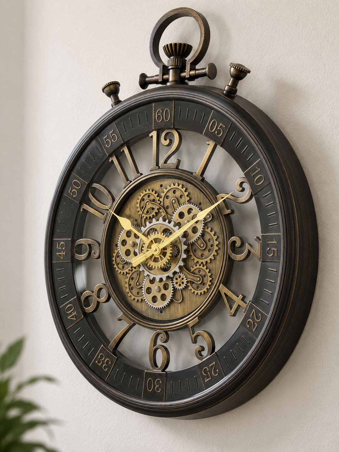 A large round wall clock with a dark bronze outer frame and a detailed central gear mechanism, mounted on a light beige wall.