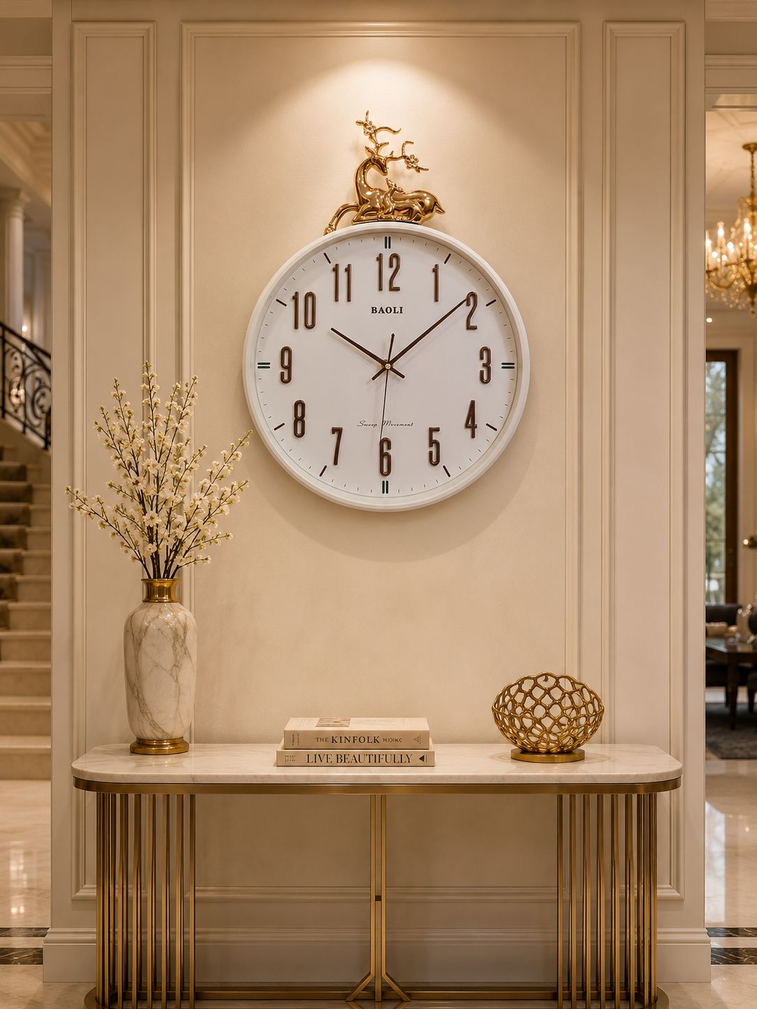 A large round wall clock with a white face and black Arabic numerals hangs on a beige paneled wall above a console table. The clock has gold-tone hands and a decorative gold top figure.