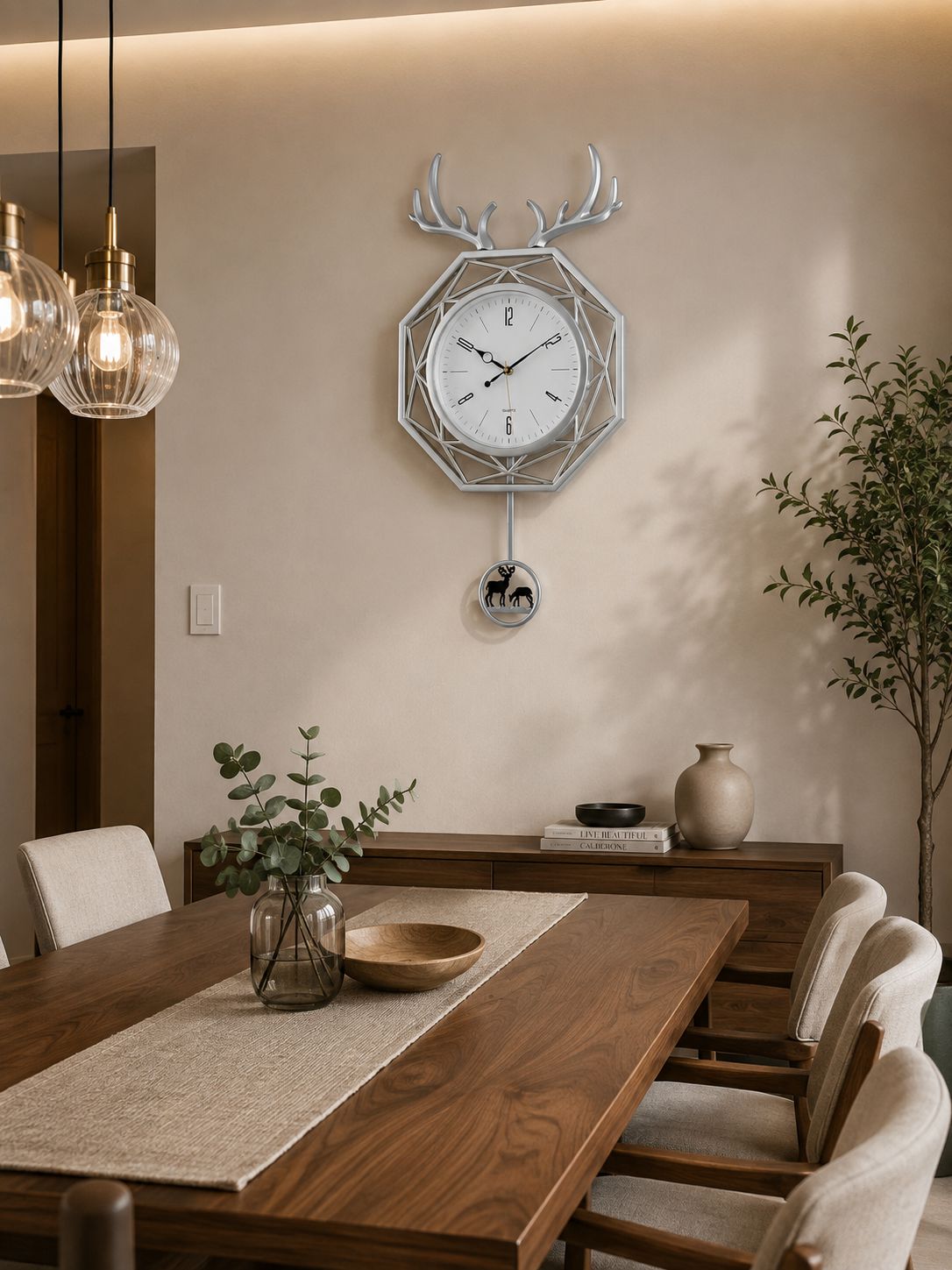 A modern geometric wall clock with antler details hangs on a beige dining room wall above a wooden table with chairs.