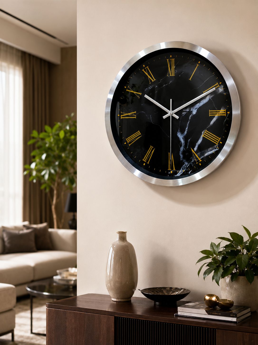 A round wall clock with a black marble-patterned face, gold Roman numerals, and a brushed silver metal frame, mounted on a beige wall in a modern living room setting.
