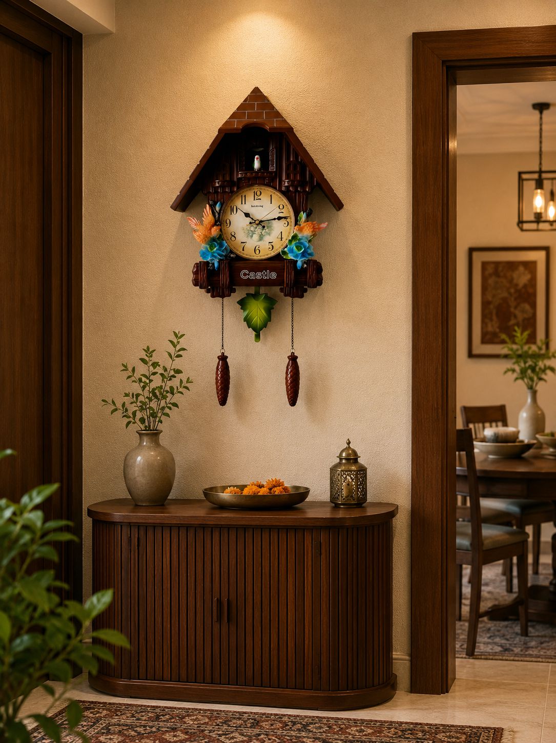 A traditional cuckoo clock with a house-shaped roof hangs on a beige wall above a dark wood console table in a warm, decorated interior.