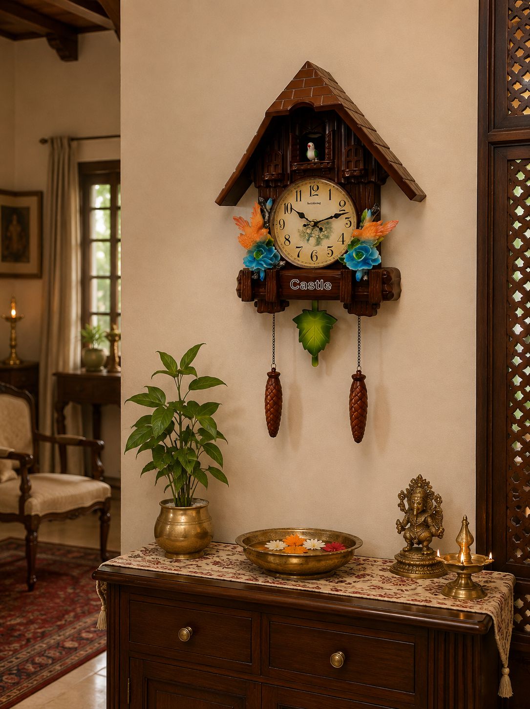 A traditional wooden cuckoo wall clock with a brown shingled house roof, cream clock face, and colorful floral accents, mounted on a beige wall above a wooden console table with a plant and brass decor.