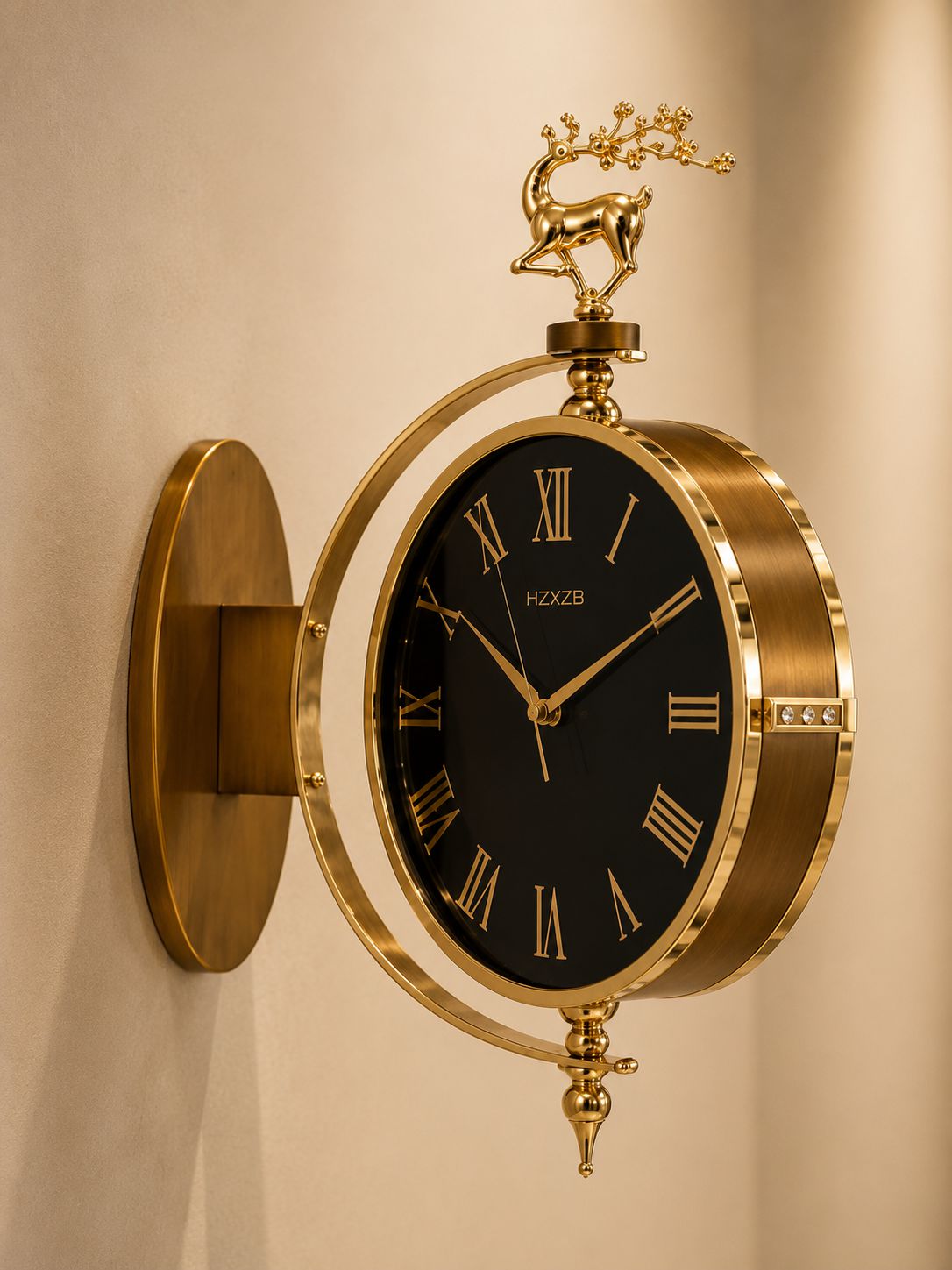 A wall-mounted decorative clock with a black dial, gold Roman numerals, and a polished gold metal frame and wall mount. A small gold deer figurine sits atop the frame, and the brand name 'HOOOOO' is visible on the clock face.