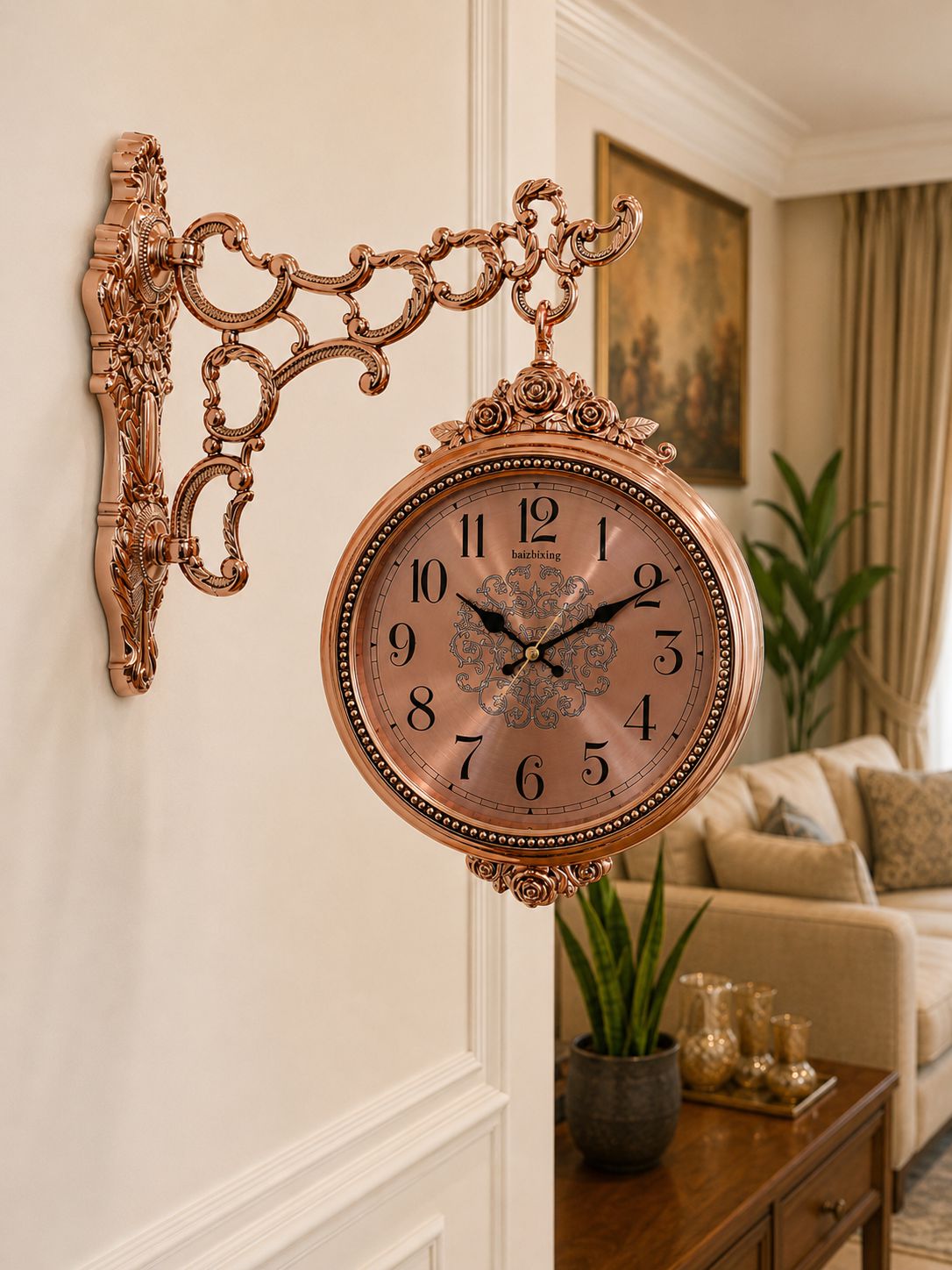 An ornate copper-toned wall clock with a decorative scrollwork bracket and a round clock face, mounted on a white wall in a styled living room interior.
