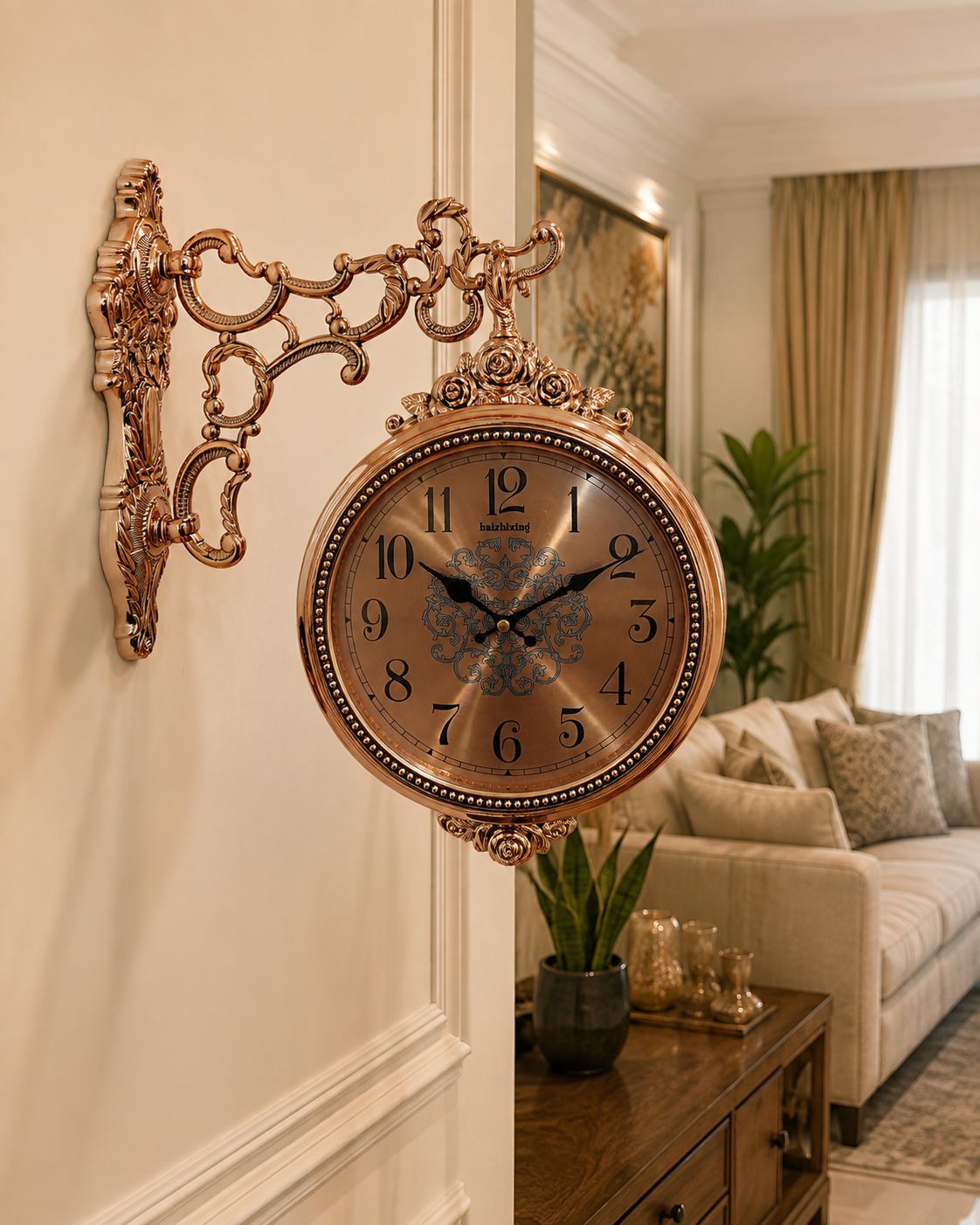 An ornate round wall clock with a bronze-finished scrollwork mount, displayed on a cream-colored wall in a beautifully decorated living room.