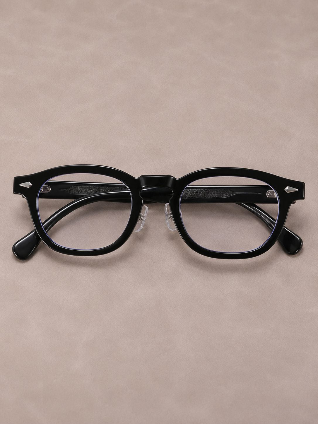 Black acetate round eyeglasses with clear lenses, displayed on a textured beige background.