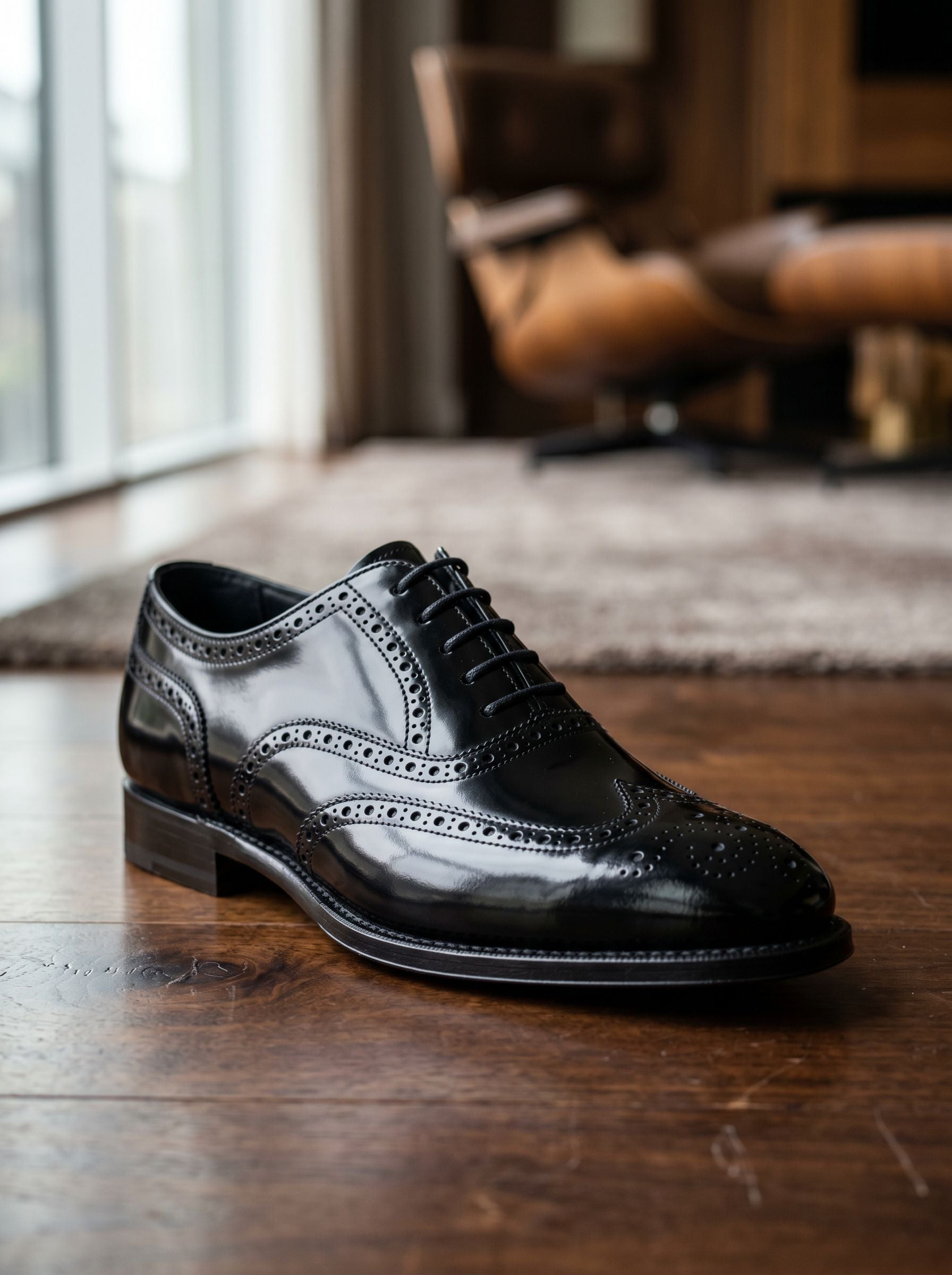 Black dress shoe on a wooden floor with a blurred background