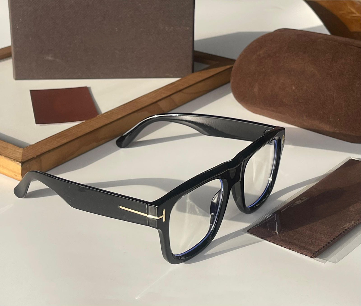 Black eyeglasses with gold accents on a white surface with brown cases.