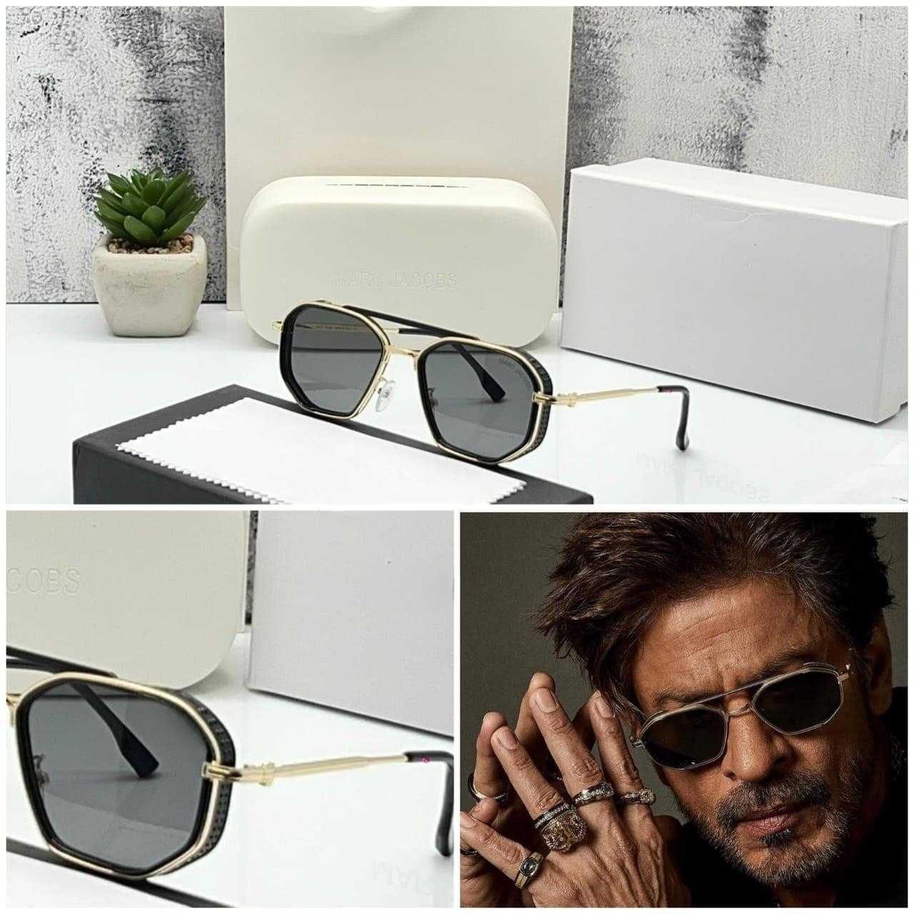 Black hexagonal sunglasses with gold frame displayed on a box/packaging.