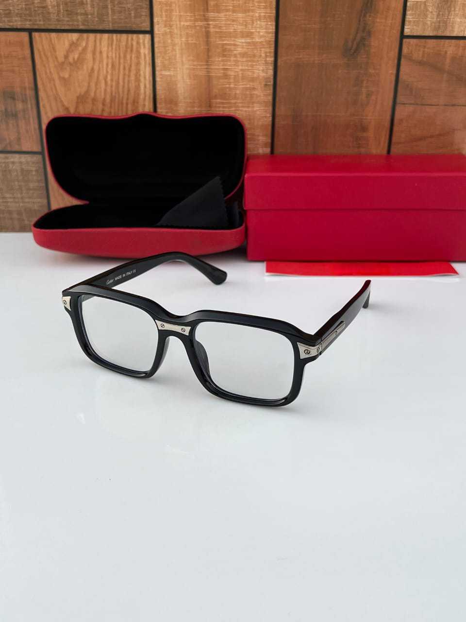 Black square eyeglasses frame with clear lenses and silver metal rivet accents, displayed with a red designer case.