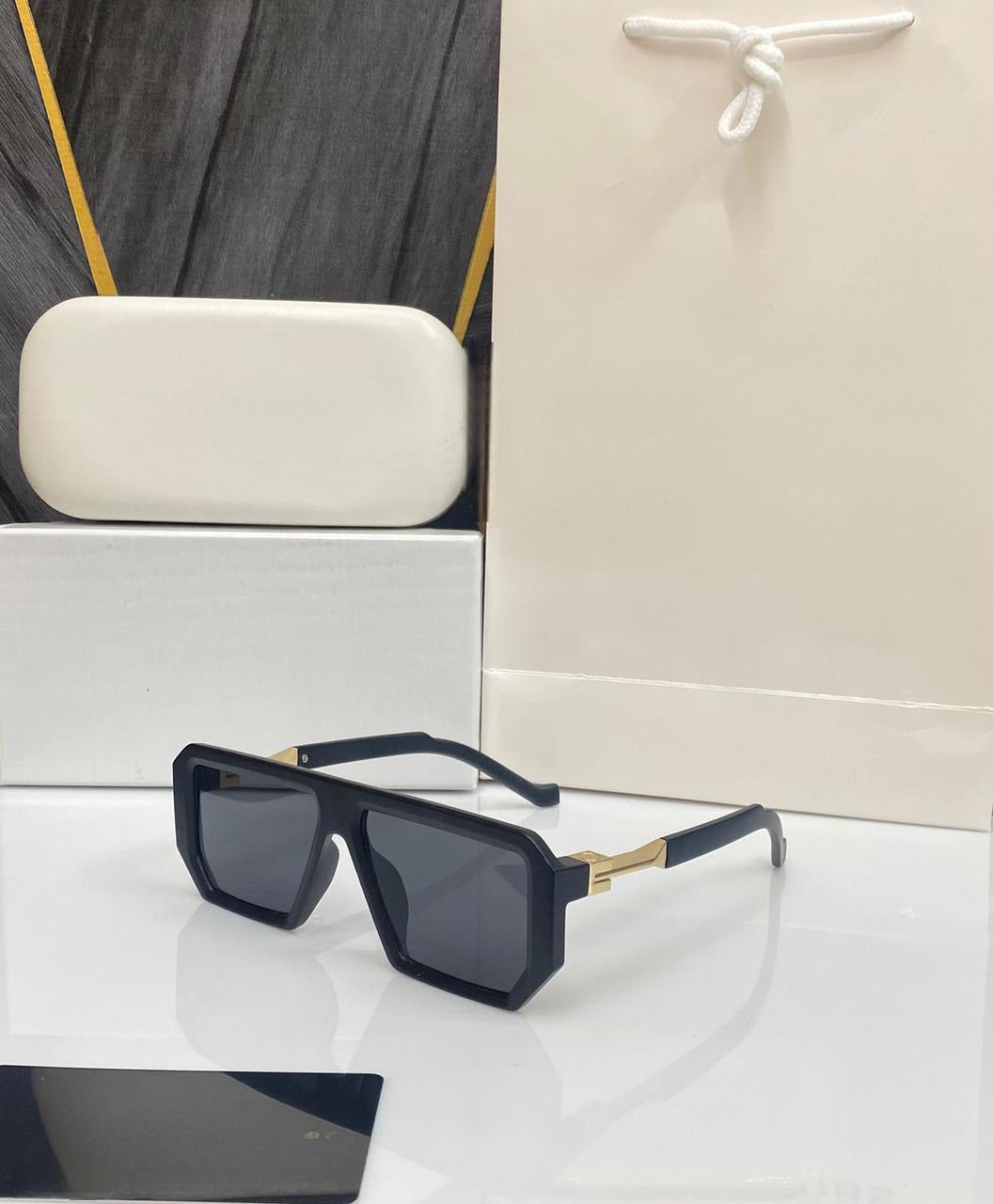 Bold black square sunglasses with dark lenses and gold metal detail on the side