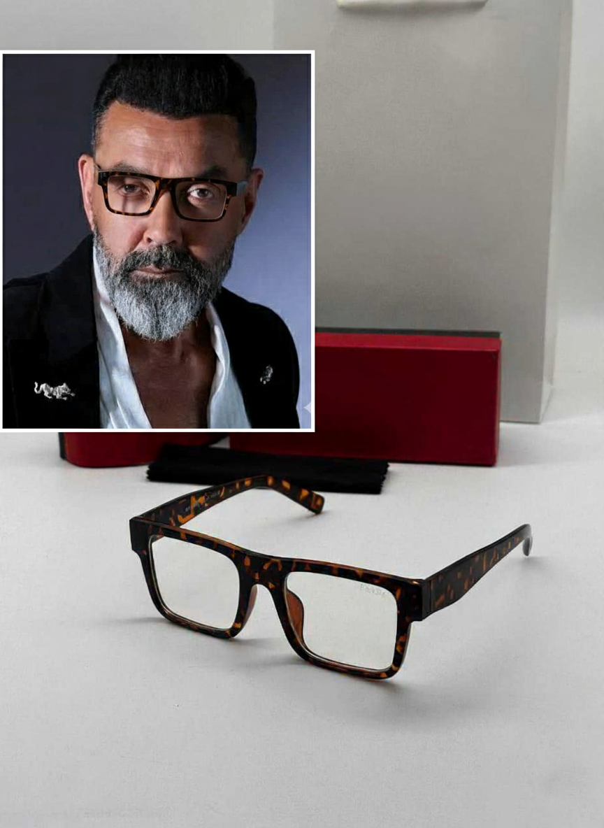 Bollywood actor Bobby Deol wearing tortoiseshell rectangle sunglasses in a snake print shirt.