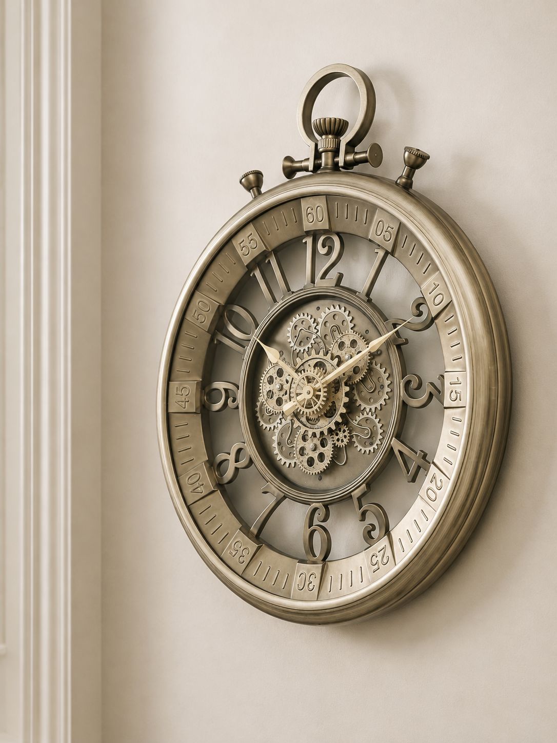 An antique-style round wall clock with a metallic bronze finish, featuring a skeletonized center showing intricate gears and cogs, set against a warm beige wall.