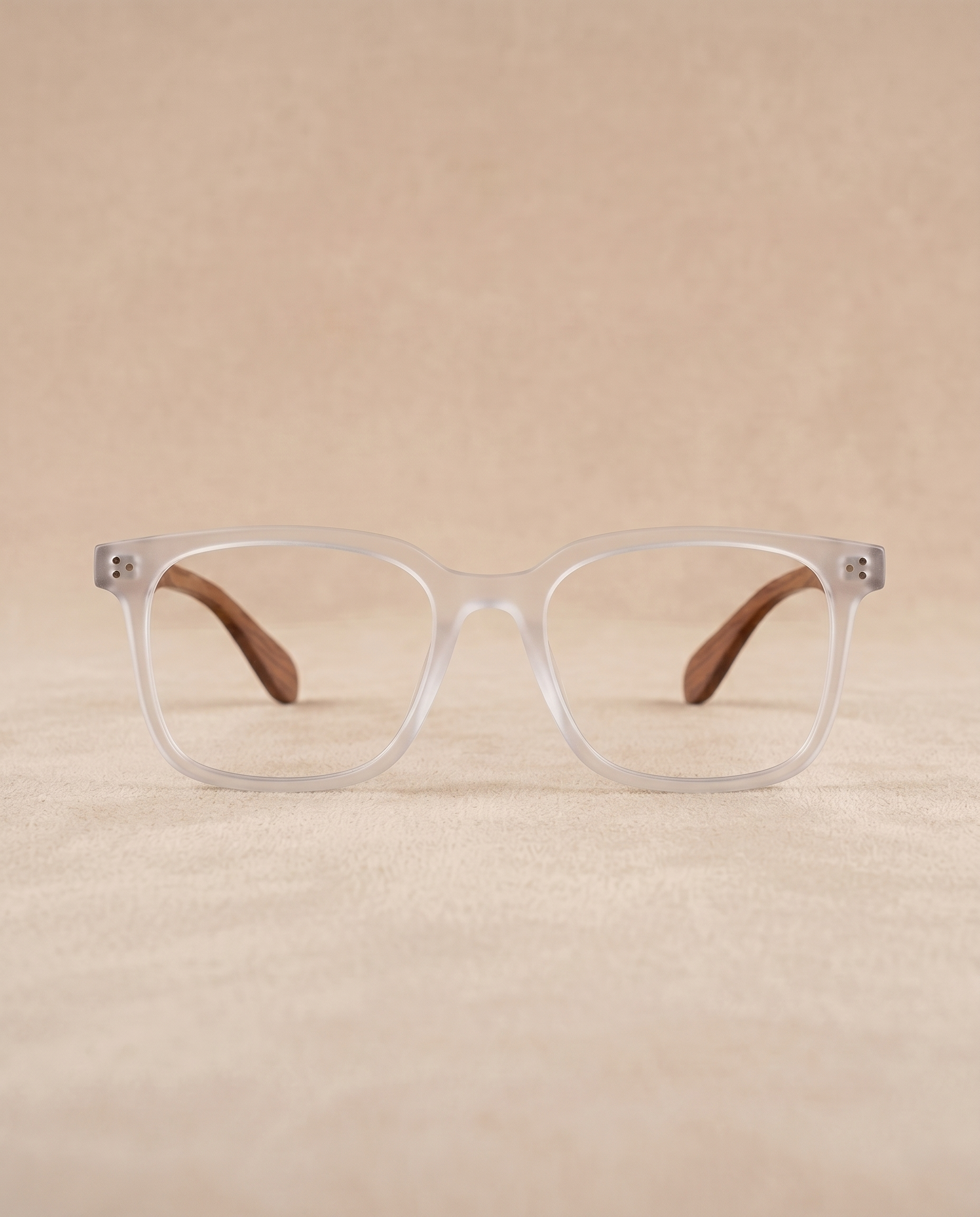 Clear eyeglasses with brown temple tips on a beige background