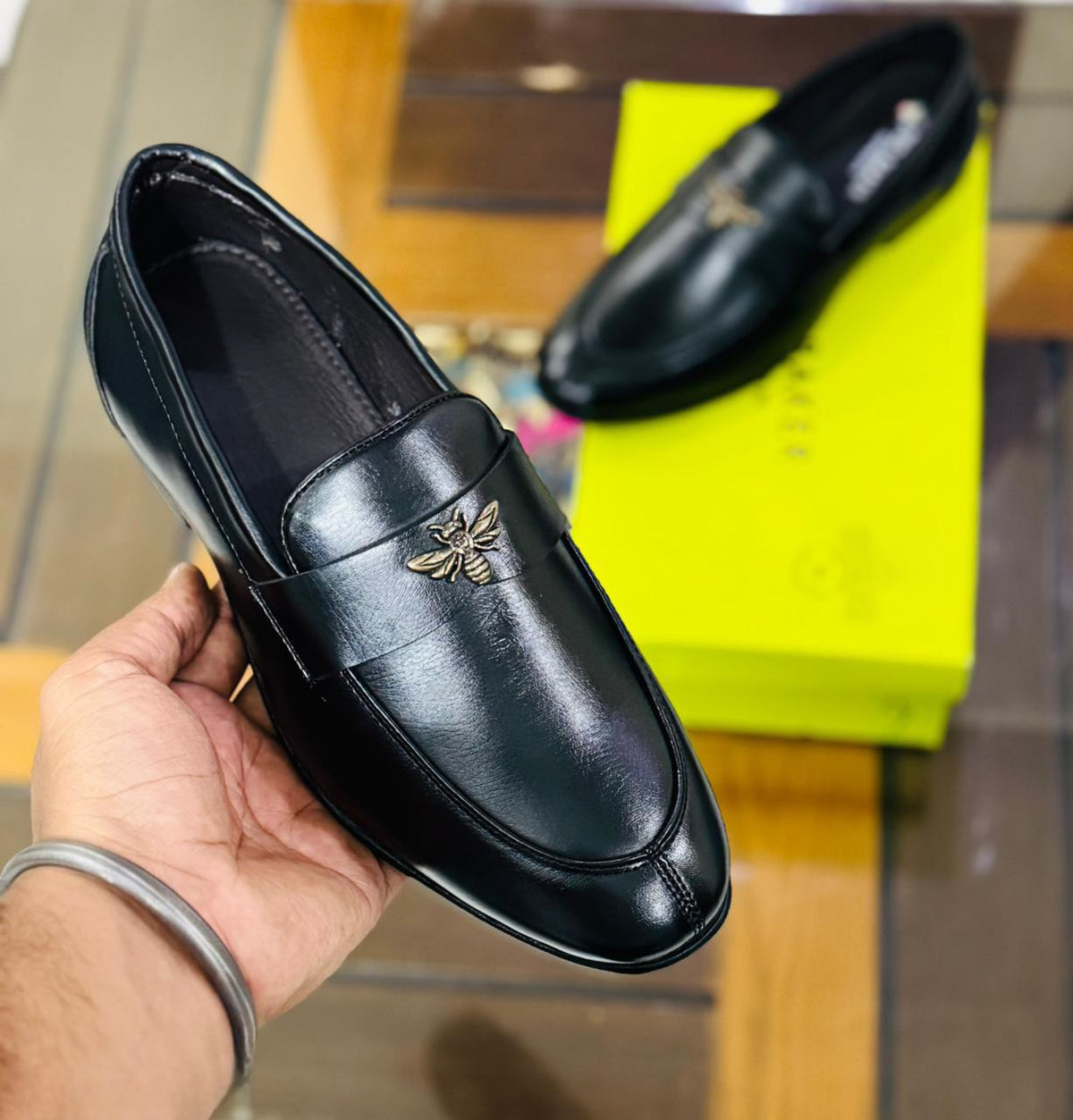 Close-up of black loafer with bee emblem and suede faux leather texture