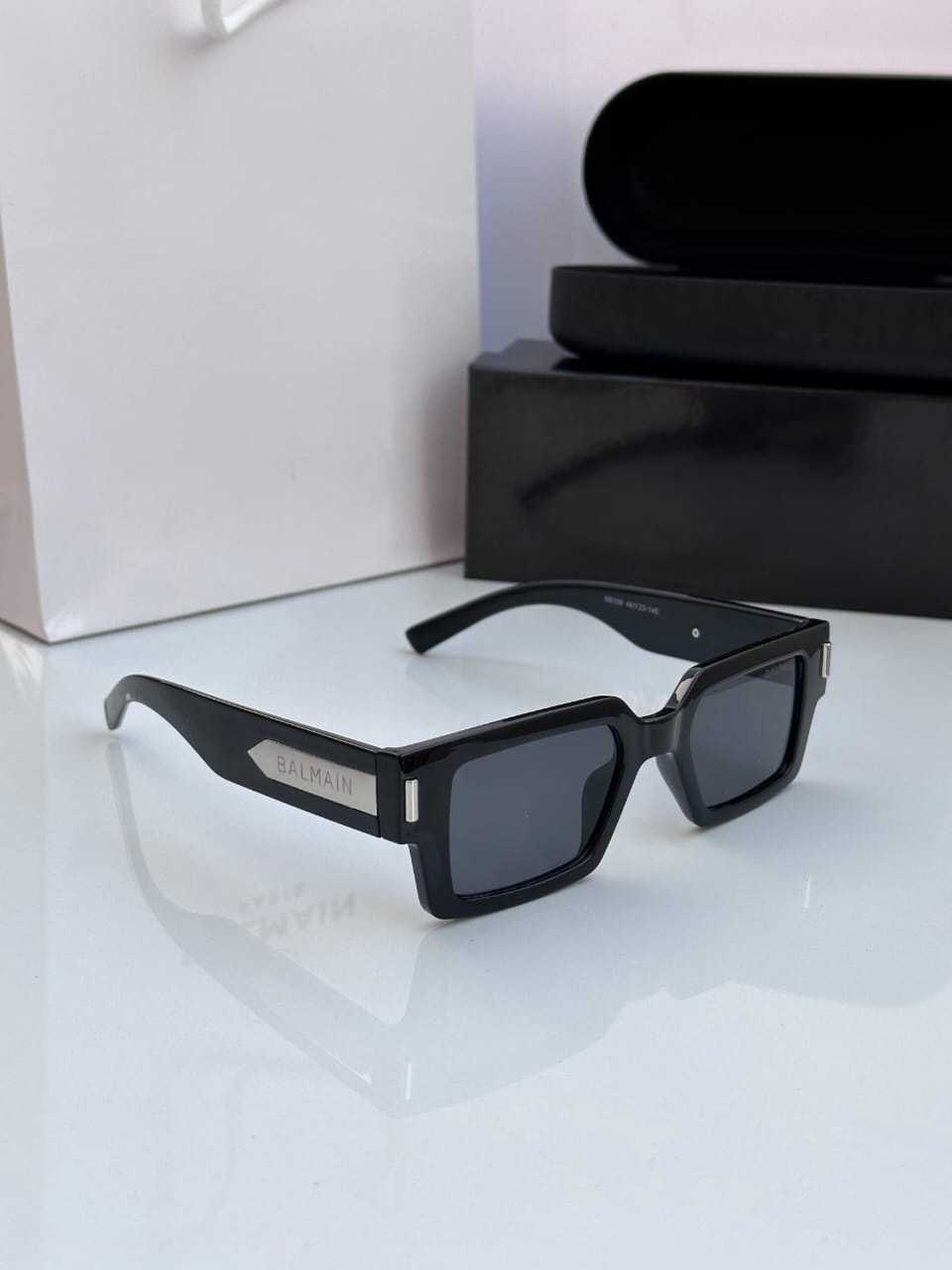 Close-up of black rectangle sunglasses with silver style designer metal detail.