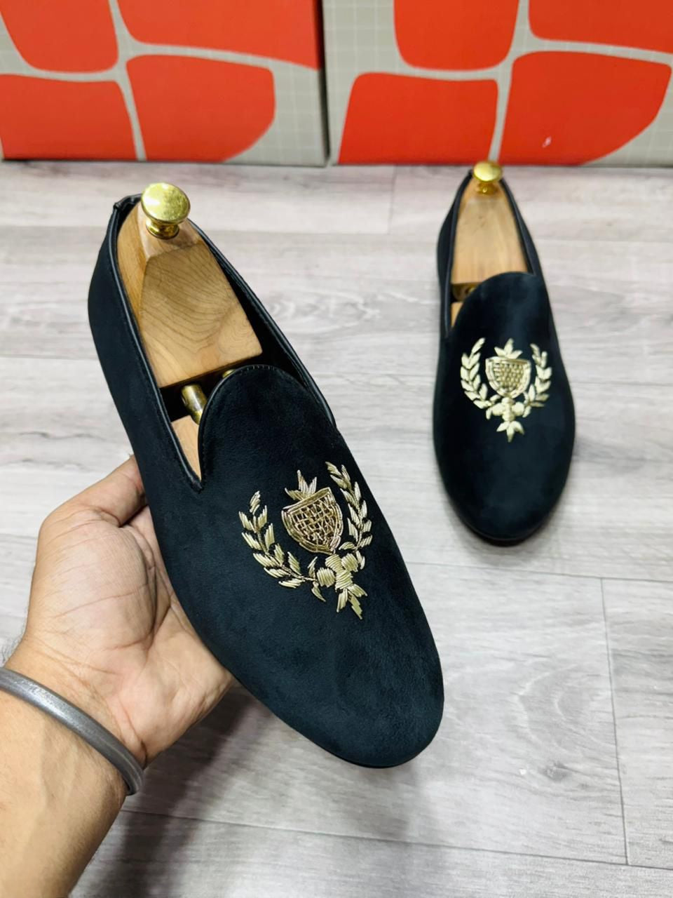 Close-up of golden crest embroidery on the velvet faux leather upper of the loafer.