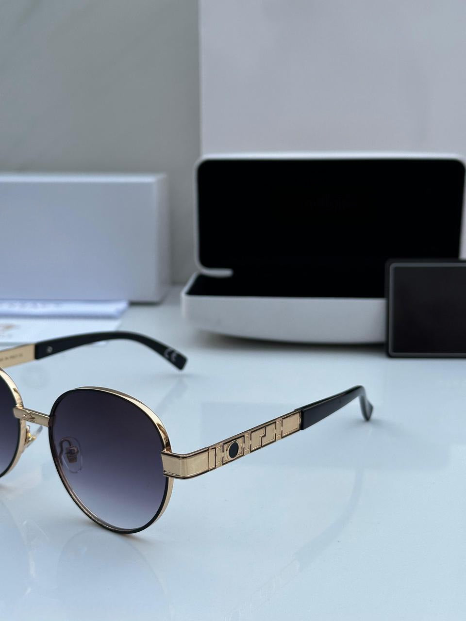 Close-up of the Gold Round Sunglasses temple, showing black earpiece and decorative metal detail.