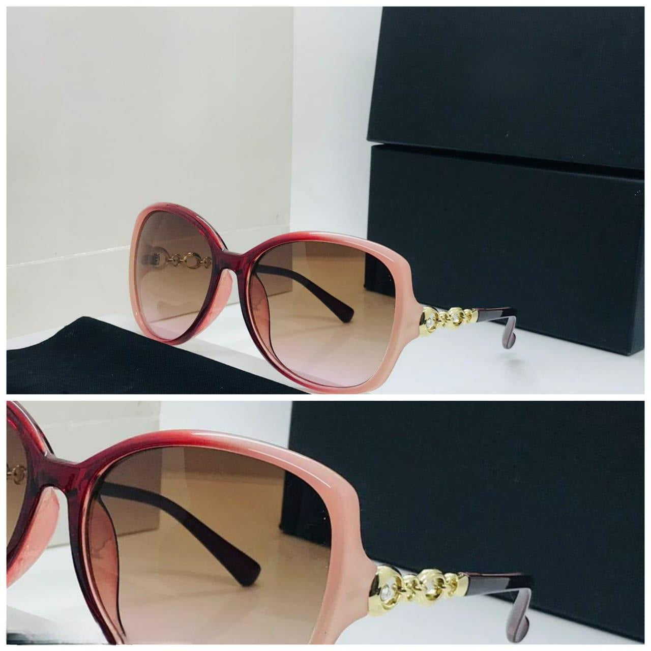 Close-up of the pink ombre sunglasses showing the gold chain link detail on the temple.