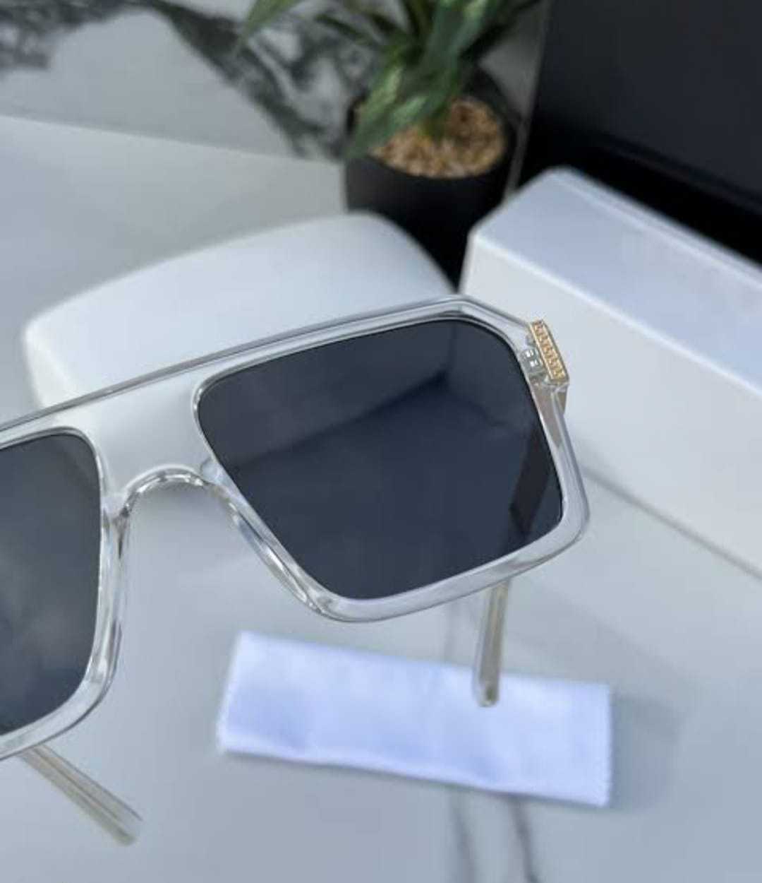 Close-up of transparent square sunglasses, highlighting the dark lenses and frame detail.