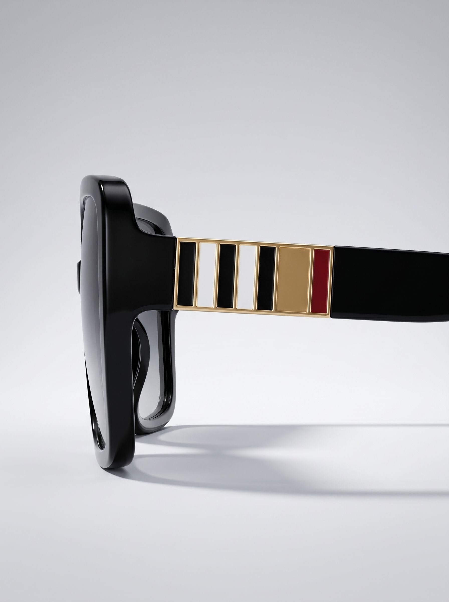 Close-up side profile of premium black sunglasses with gold striped temple detailing