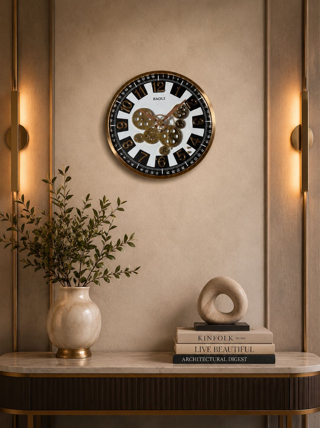 Decorative wall clock on a beige wall with a vase and books on a table below.