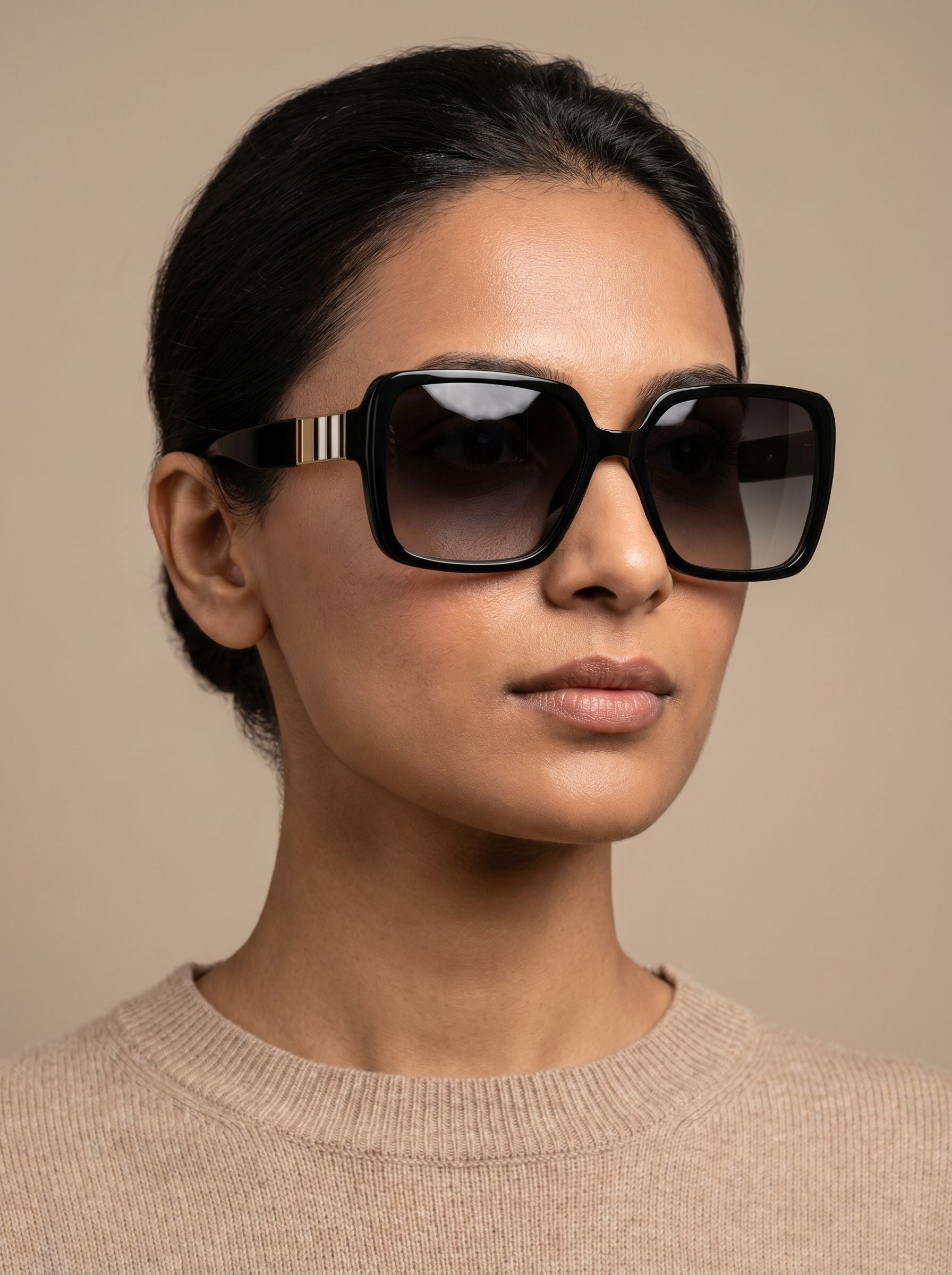 Female model wearing oversized black luxury sunglasses with elegant neutral styling