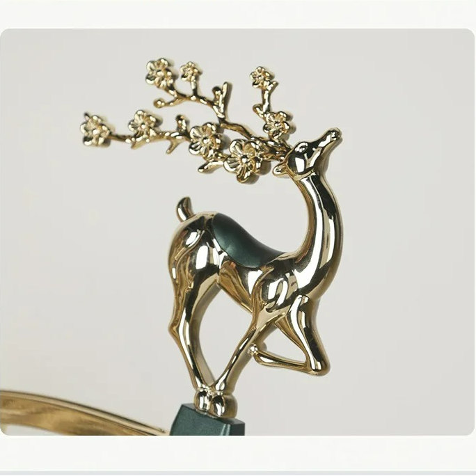 Gold deer ornament with floral branch on a white background