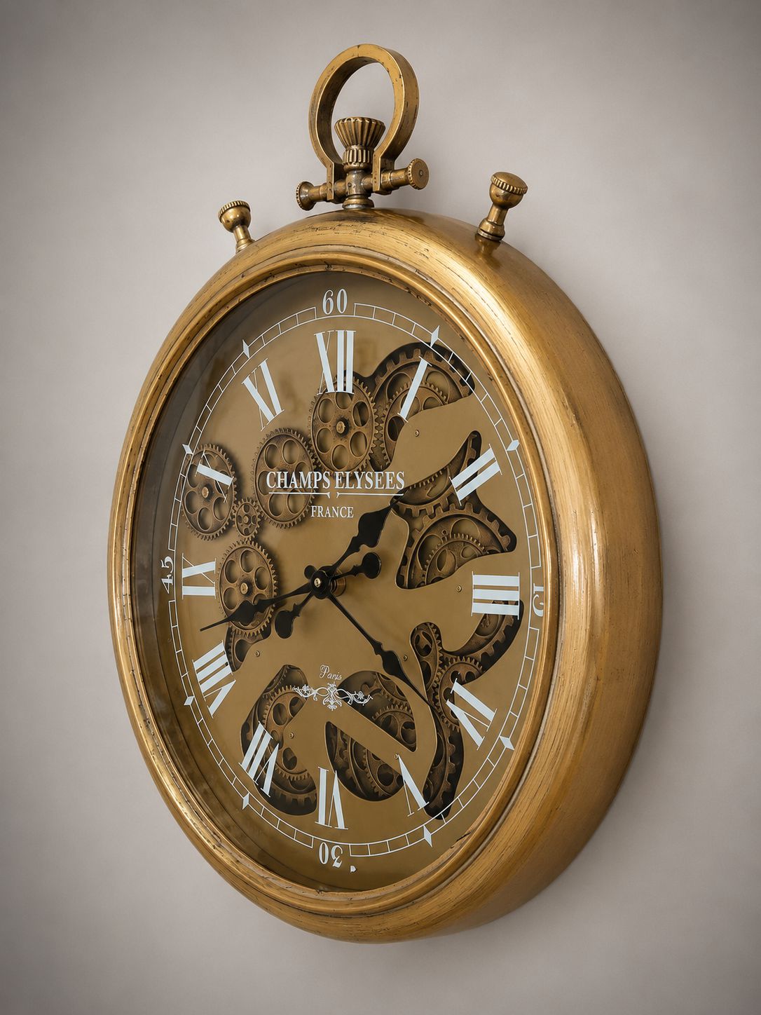 Gold wall clock with intricate design on a beige background