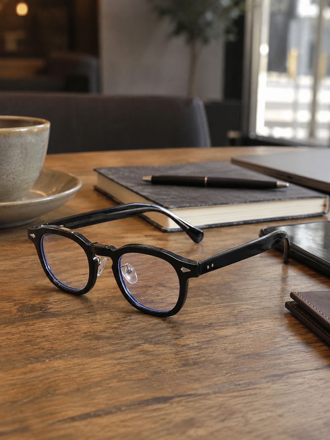Johnny Depp inspired black eyeglasses styled on a wooden desk with notebook and coffee