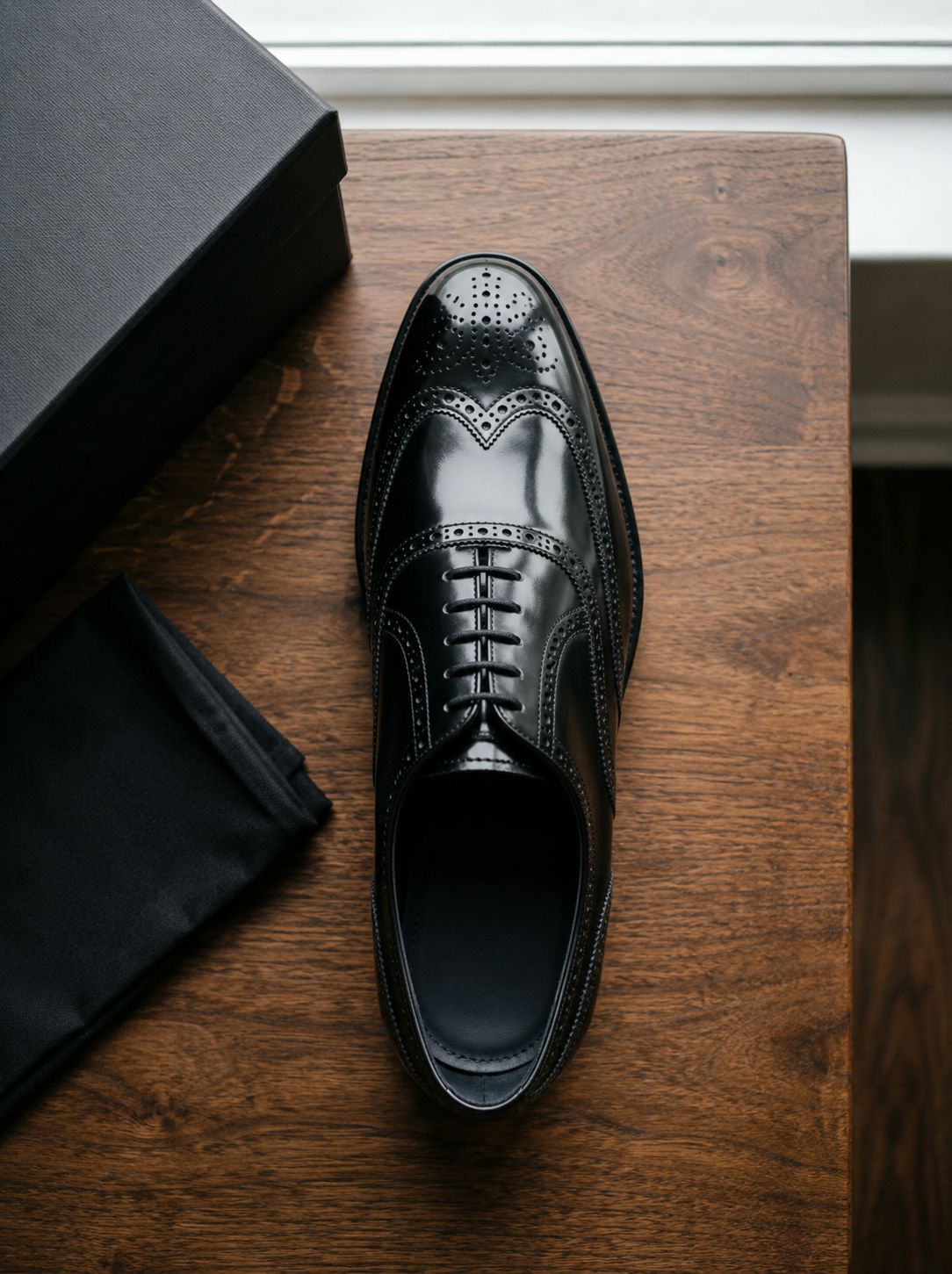 Luxury black patent brogue Oxford shoe top view on wooden table