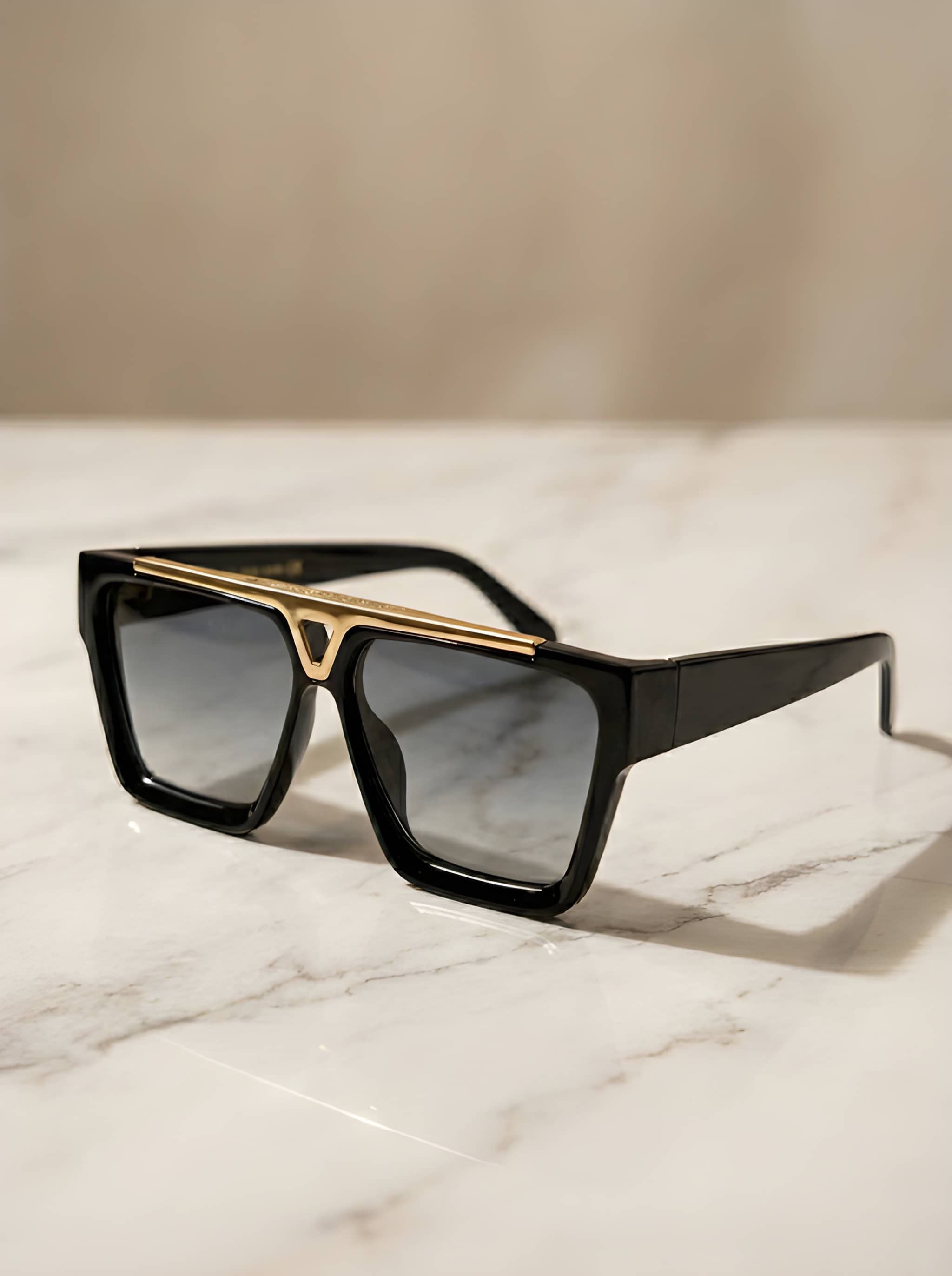 Luxury oversized black square sunglasses with gold top bar detail on marble surface