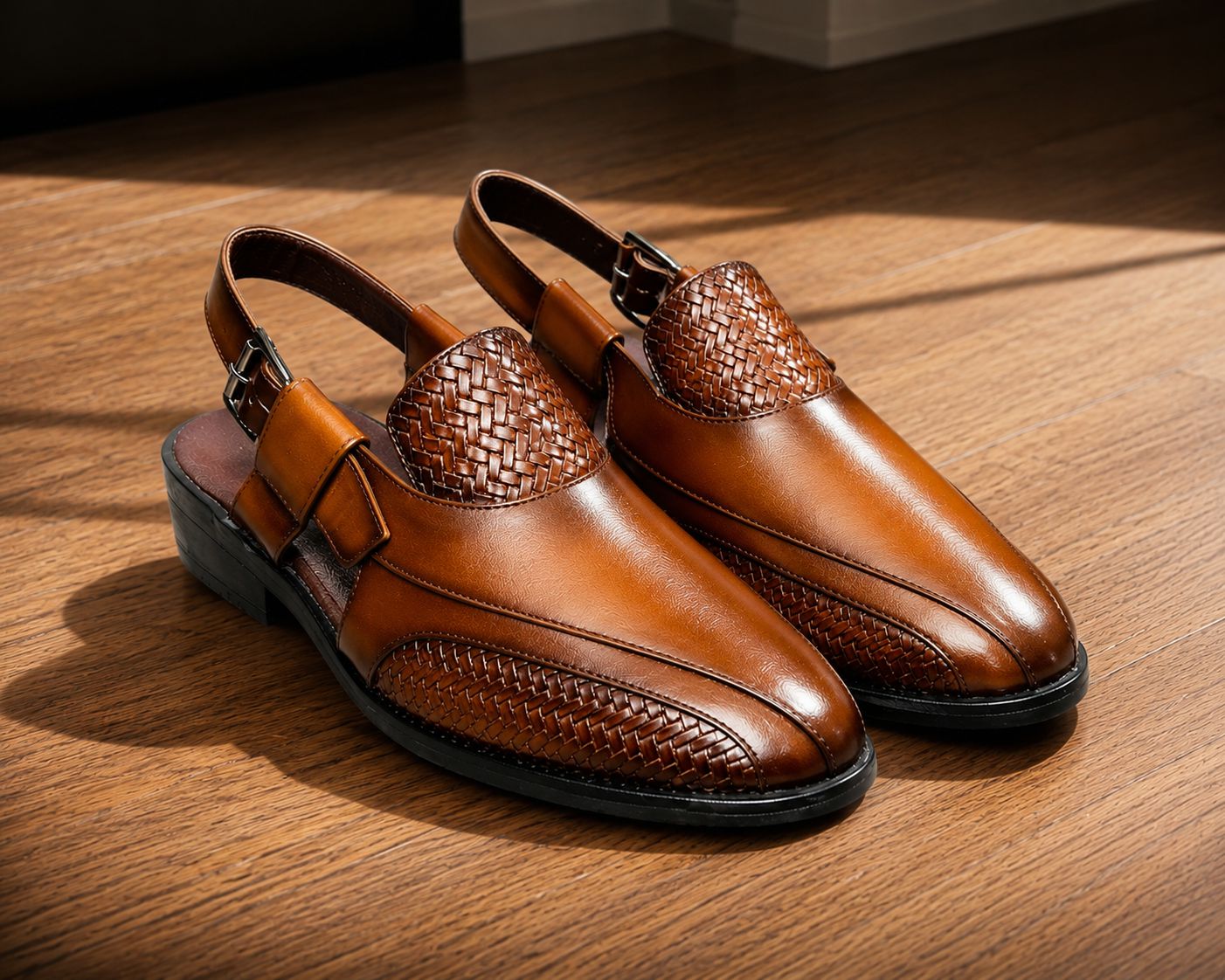 Pair of brown leather shoes with woven detailing on a wooden floor.