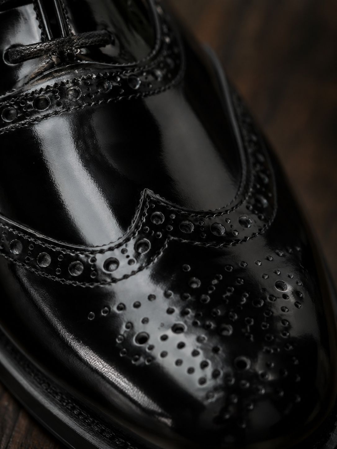 Shiny black dress shoe on a wooden surface