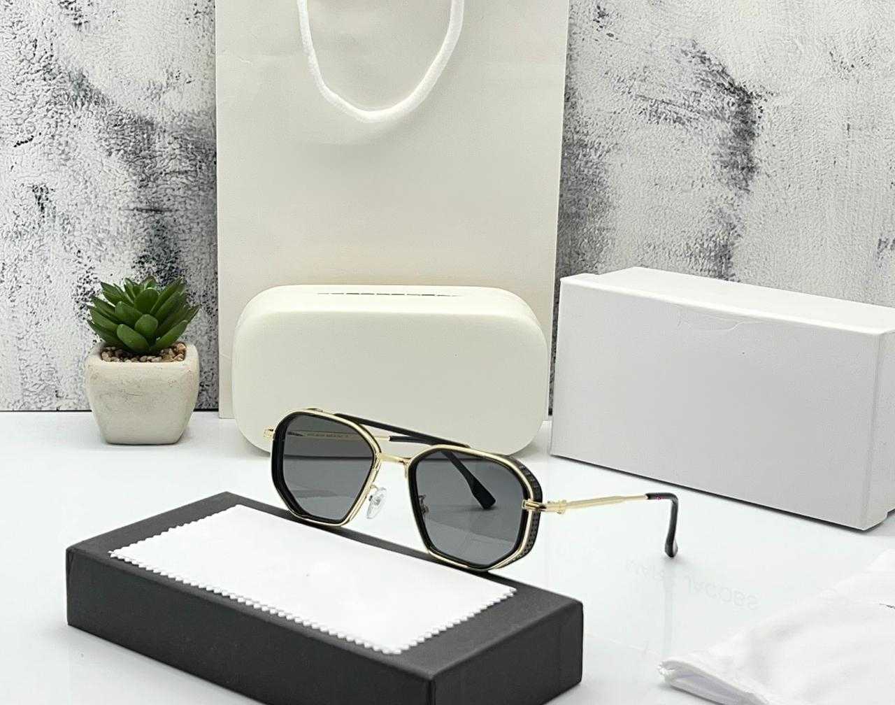 Side view of black hexagonal sunglasses showing the gold metal frame and temple arm.
