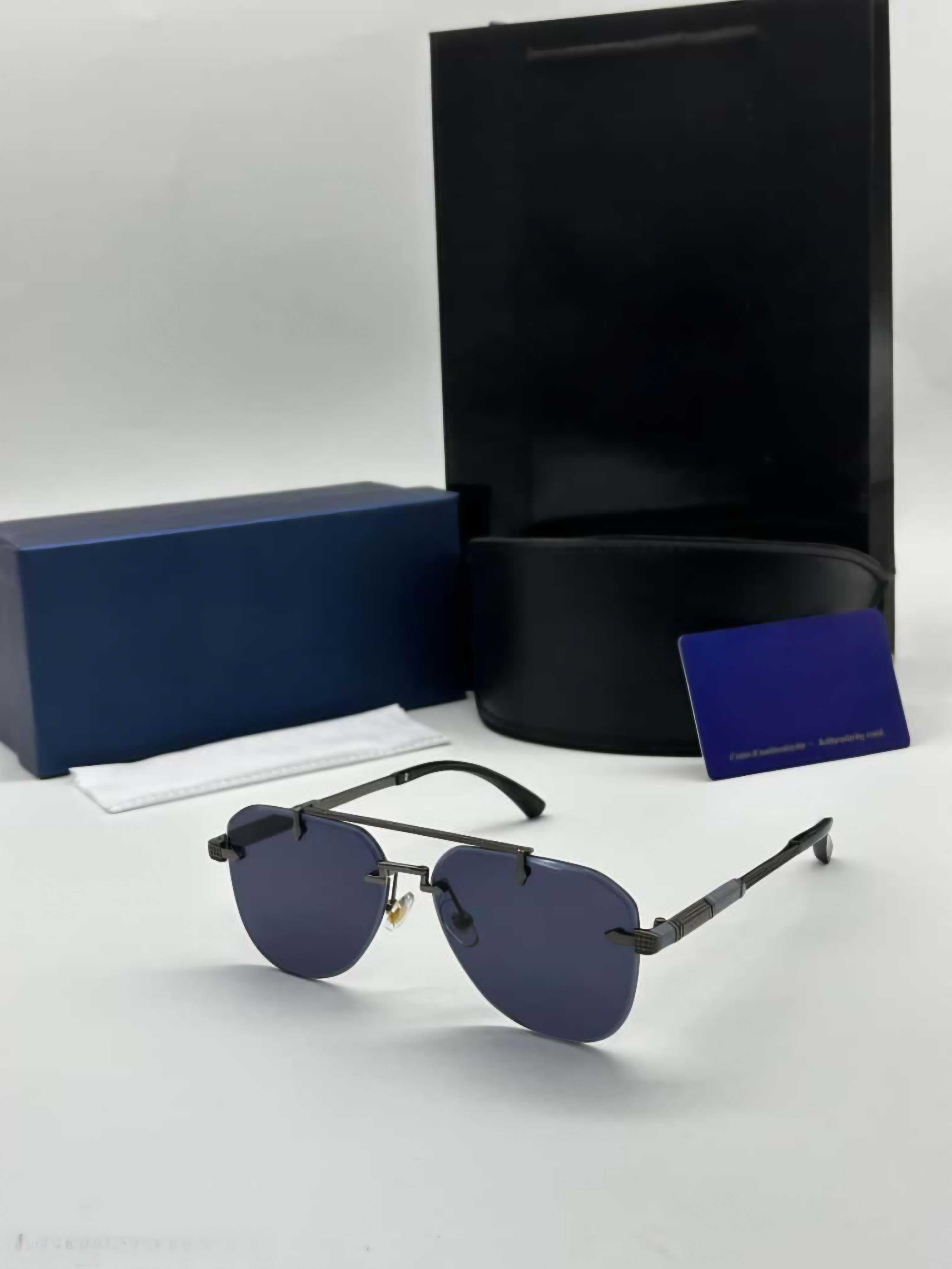 Sleek rimless aviator sunglasses with gunmetal black metal frame and dark blue/grey lenses.