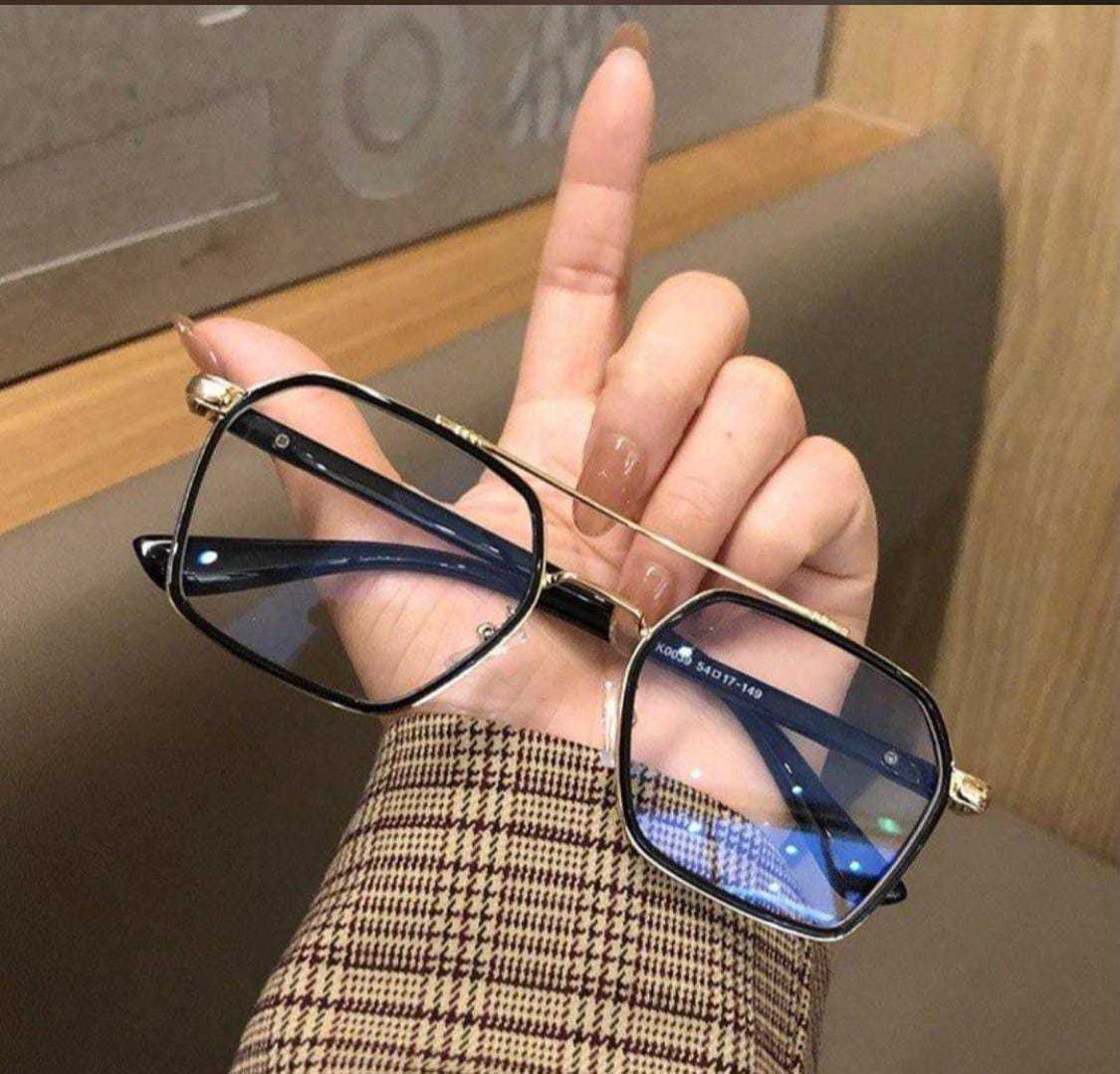 Stylish black and gold hexagonal glasses held by a hand; shows the temple detail and gold bridge.