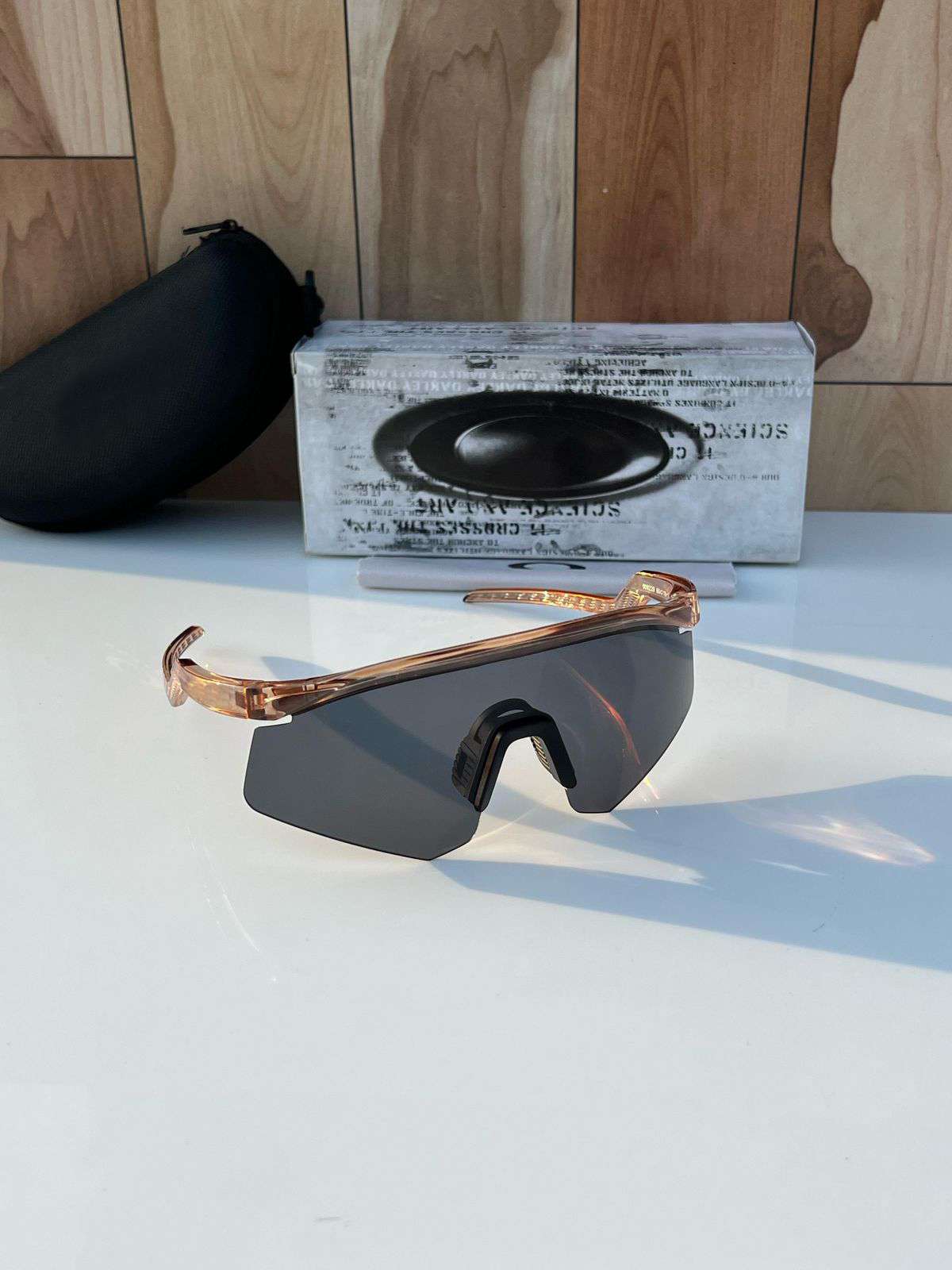 Sunglasses with a reflective lens on a white surface with a wooden background
