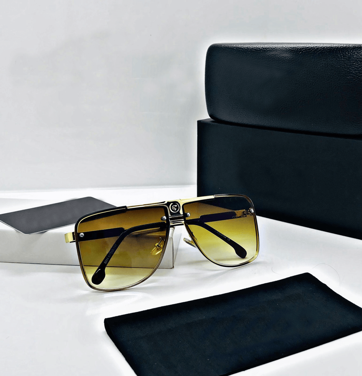 Sunglasses with gold gradient lenses on a white surface with black case and cloth.