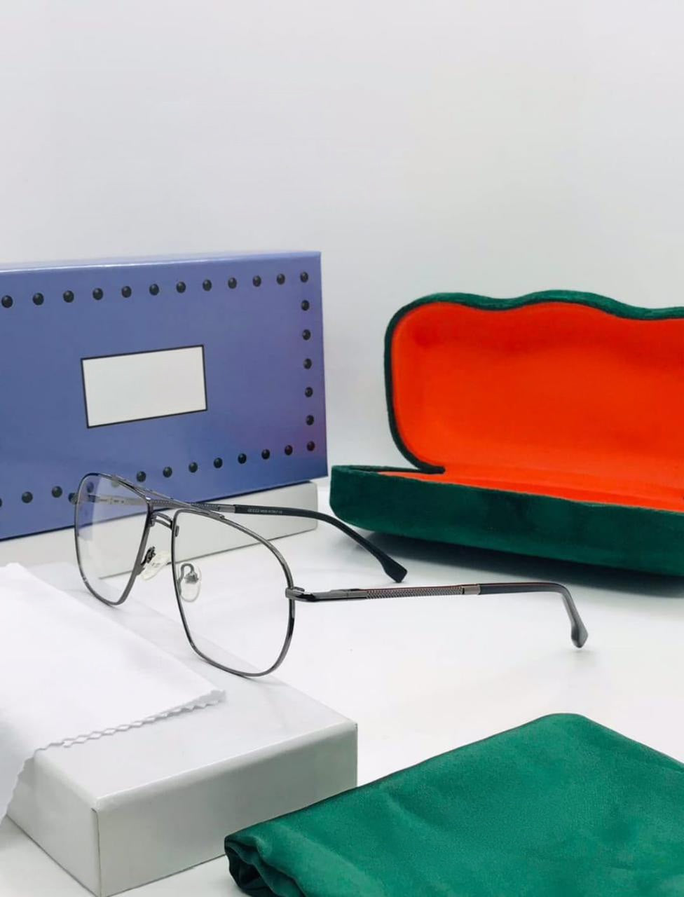 Thin gunmetal metal eyeglasses with a square/geometric frame shape, shown with an open green and red hard case